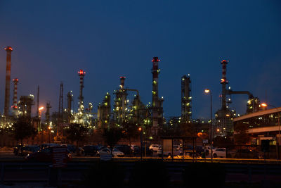 Illuminated factory against clear blue sky at night