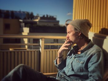 Young man sitting in sun smoking