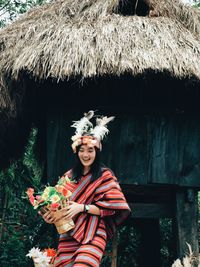 Smiling young woman standing against hut