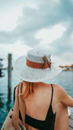 Midsection of woman wearing hat against sea