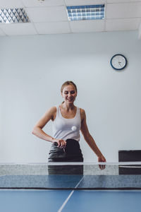 Smiling woman playing table tennis indoors