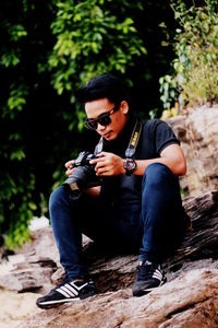 Young man wearing sunglasses sitting on rock