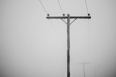 Low angle view of electricity pylon against clear sky