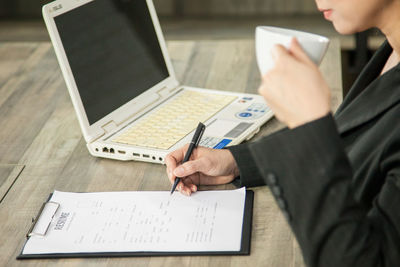 Midsection of woman using laptop on table