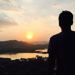 Rear view of silhouette man standing against sky during sunset