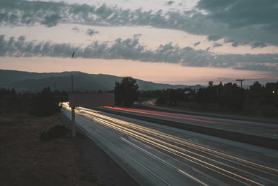 Light trails on road against sky