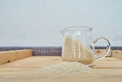 Close-up of rice in container on wooden table