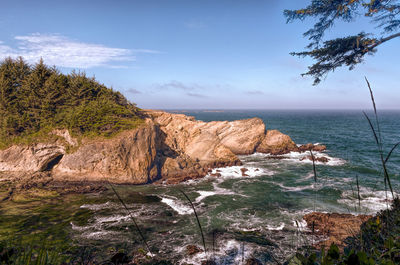 Rock formations at cape arago state park against cloudy sky