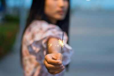 Midsection of woman holding sparkler outdoors