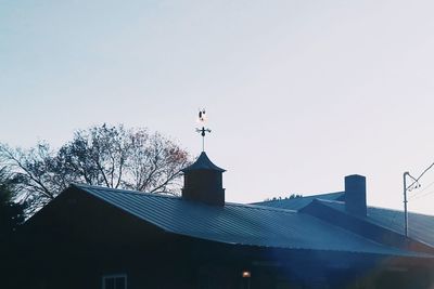 Low angle view of cross on roof of building against clear sky