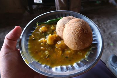 High angle view of hand holding soup in bowl on table