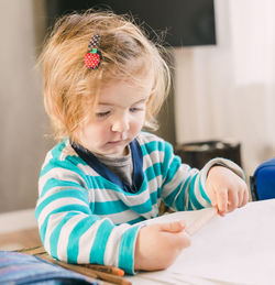 Close-up of cute girl holding paper while sitting at home