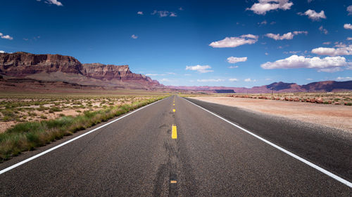 Road leading towards mountain against sky