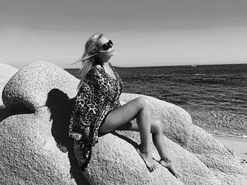 Young woman sitting on rock at beach