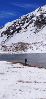 Person walking on snow covered mountain against sky