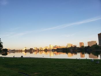 Scenic view of river by buildings against sky during sunset