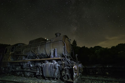 Abandoned vehicle on field against sky at night