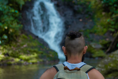 Rear view of man standing against waterfall