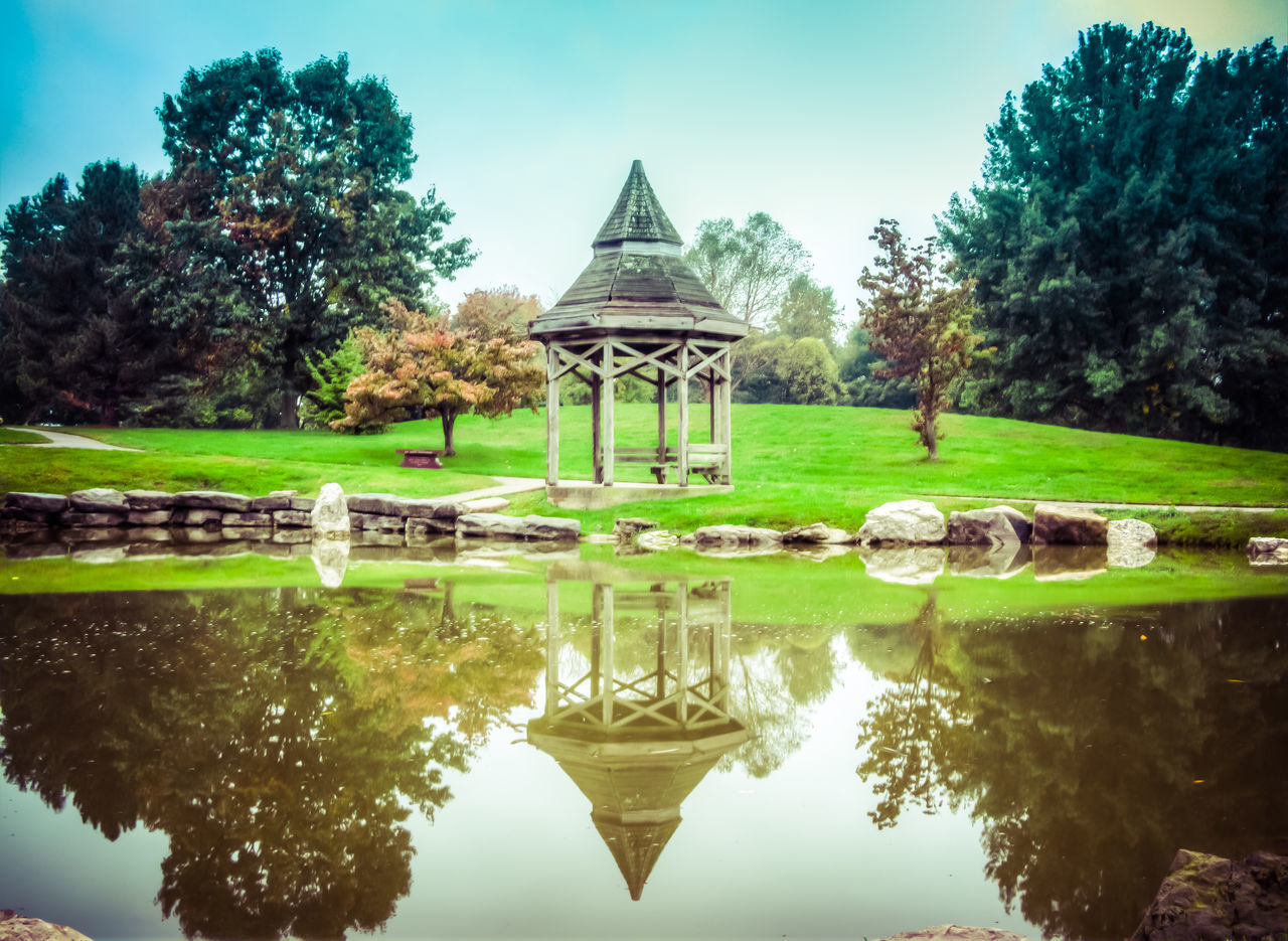 reflection, water, tree, architecture, built structure, waterfront, pond, standing water, lake, sky, tranquility, river, building exterior, symmetry, nature, tranquil scene, canal, bridge - man made structure, travel destinations, outdoors