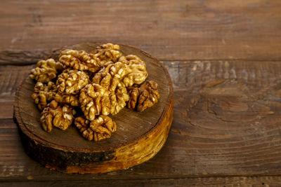 Walnuts are scattered on a round board on a wooden table. horizontal photo