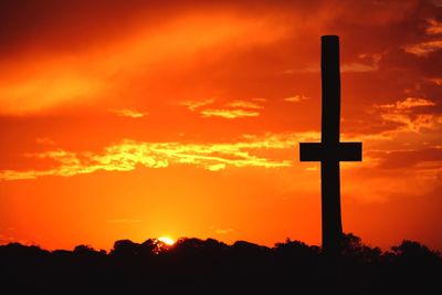 Silhouette cross against sky during sunset