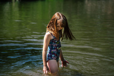 Portrait of a young happy girl playing in a river on a sunny day