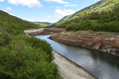 Scenic view of river by mountains against sky