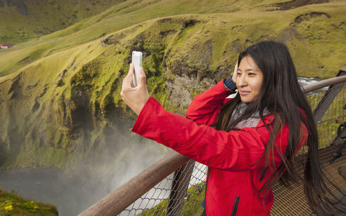 Beautiful woman taking selfie at skogarfoss waterfall in iceland