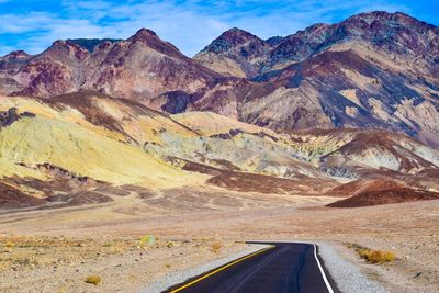 Road leading towards mountains against sky