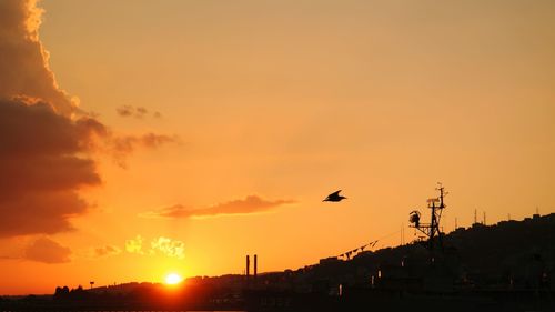 Silhouette birds flying against sky during sunset