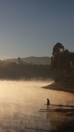 Man on lake against sky in the morning glory