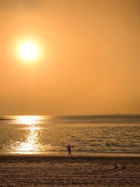 Silhouette person standing on beach against sky during sunset