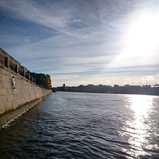 water, architecture, built structure, building exterior, sky, waterfront, sunlight, sun, reflection, sunbeam, cloud - sky, river, rippled, tranquility, nature, outdoors, tranquil scene, cloud, scenics, canal