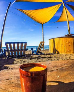 Tea light on beach against blue sky