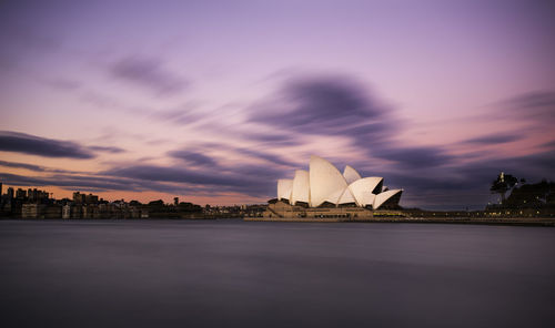 View of city at waterfront against cloudy sky
