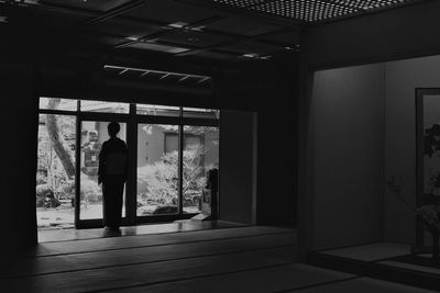 Rear view of woman standing by glass door at japanese home