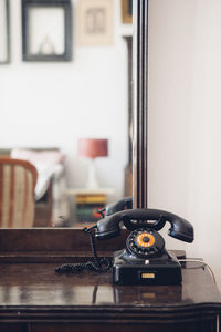 Rotary phone on table against mirror at home