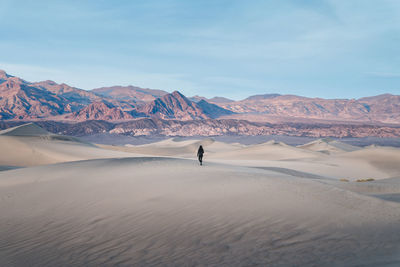 Woman walking on desert against sky