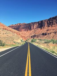 Empty road by mountains against sky