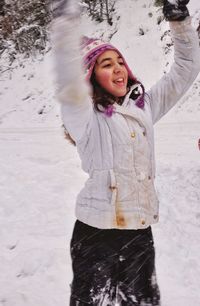 Smiling girl with arms raised standing in snow