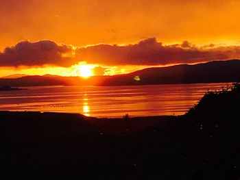 Scenic view of silhouette mountains against orange sky