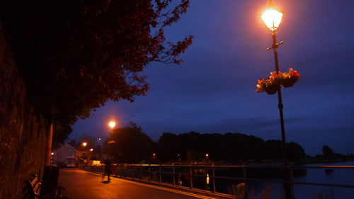 Illuminated street light against sky at night