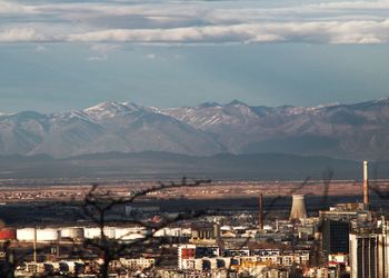 Aerial view of city and mountains against sky