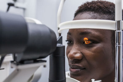 Optometrist adjusting the retinograph during study of the eyesight of a black woman