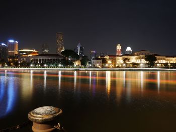 Light trails on river in illuminated city at night