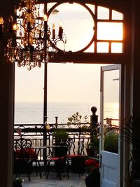 People on table by sea against sky during sunset