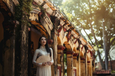 Portrait of woman standing against tree