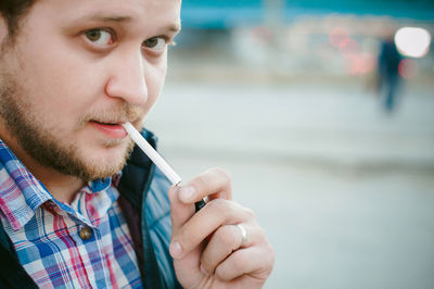 Close-up portrait of man smoking cigarette in city