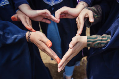 Midsection of friends joining hands on field