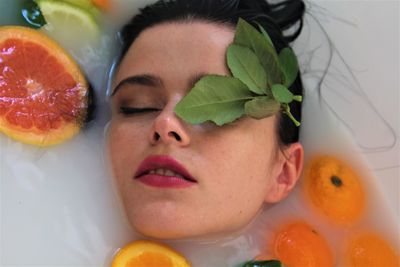 Close-up portrait of woman taking bath with fruits in bathtub